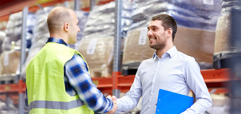 men shaking hands in warehouse, revolutionizing customer experience.